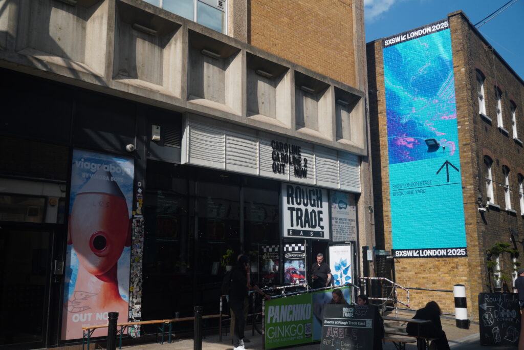 Rough Trade East with SXSW billboard – Rough Trade East record store beside towering LED screen advertising SXSW London 2025.