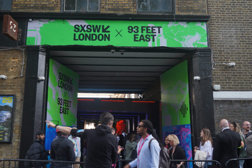 SXSW × 93 Feet East gateway – Neon‑green banner over 93 Feet East courtyard entrance during SXSW London pop‑up.